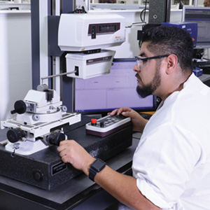 Photograph of a lab technician inspecting bearings at the Bii Facility in Los Alamitos, California.